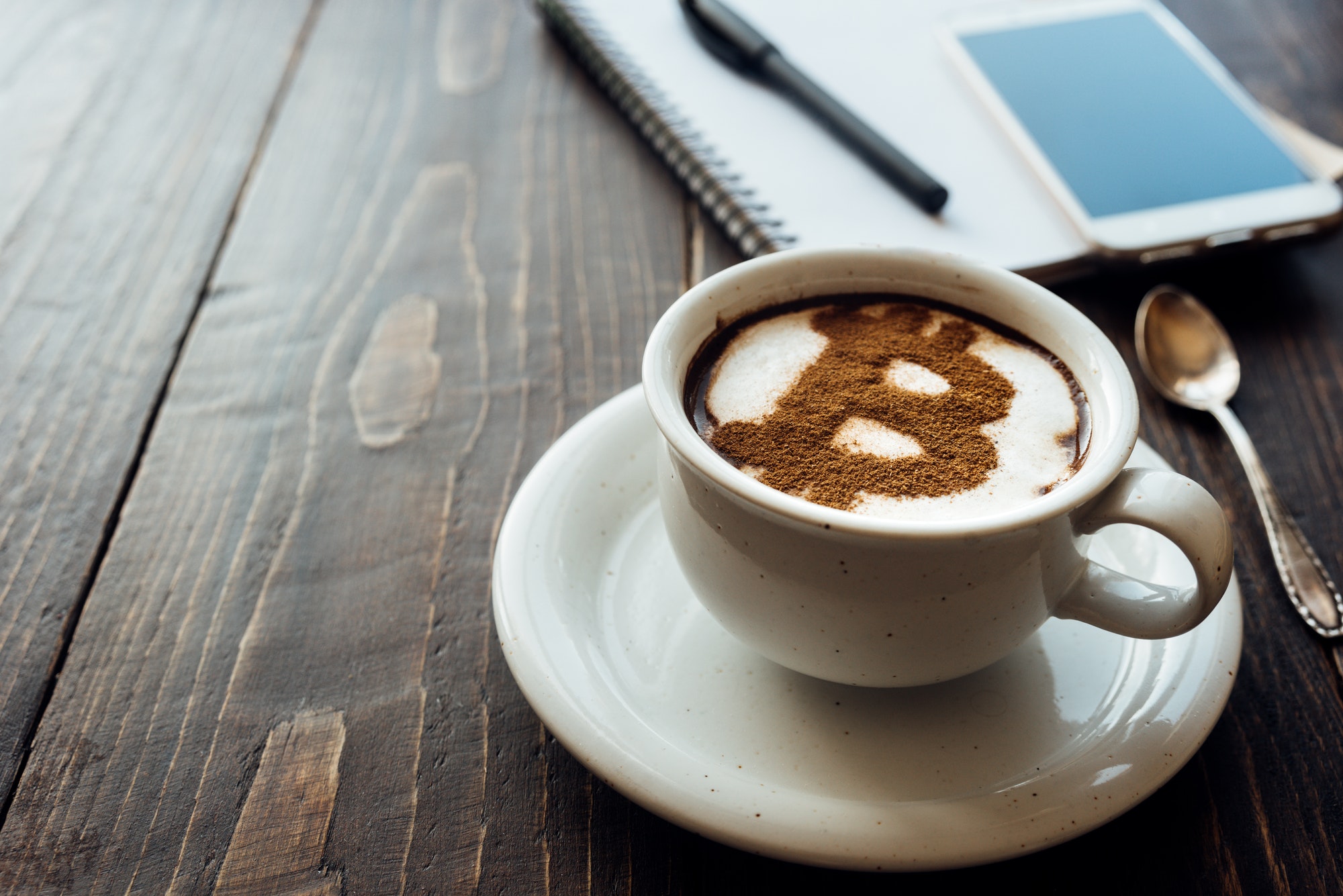 Cup of coffee with bitcoin symbol on milk foam